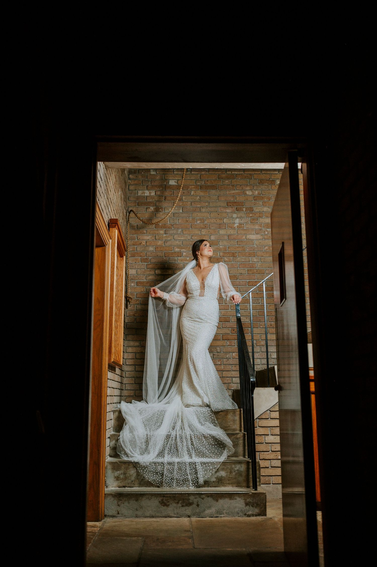 A series of photos showing a bride in a white lace wedding gown posing on rustic brick stairs in moody lighting.