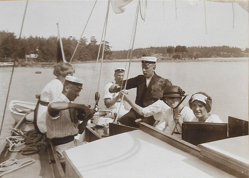 Vanha valokuva 1920 -luvulta missä ihmiset nauttivat viiniä purjeveneen kannella.