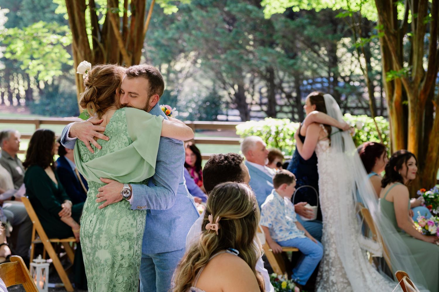 A group of dancers in a romantic slow dance outdoors with soft green foliage creating a natural backdrop.