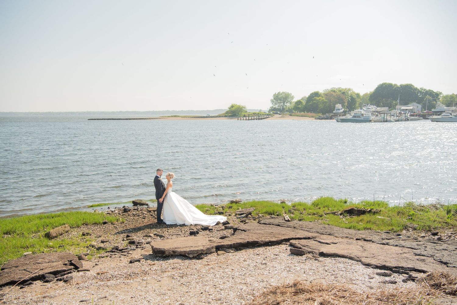 Newlywed couple shares a romantic moment by the waterfront during their wedding photoshoot.