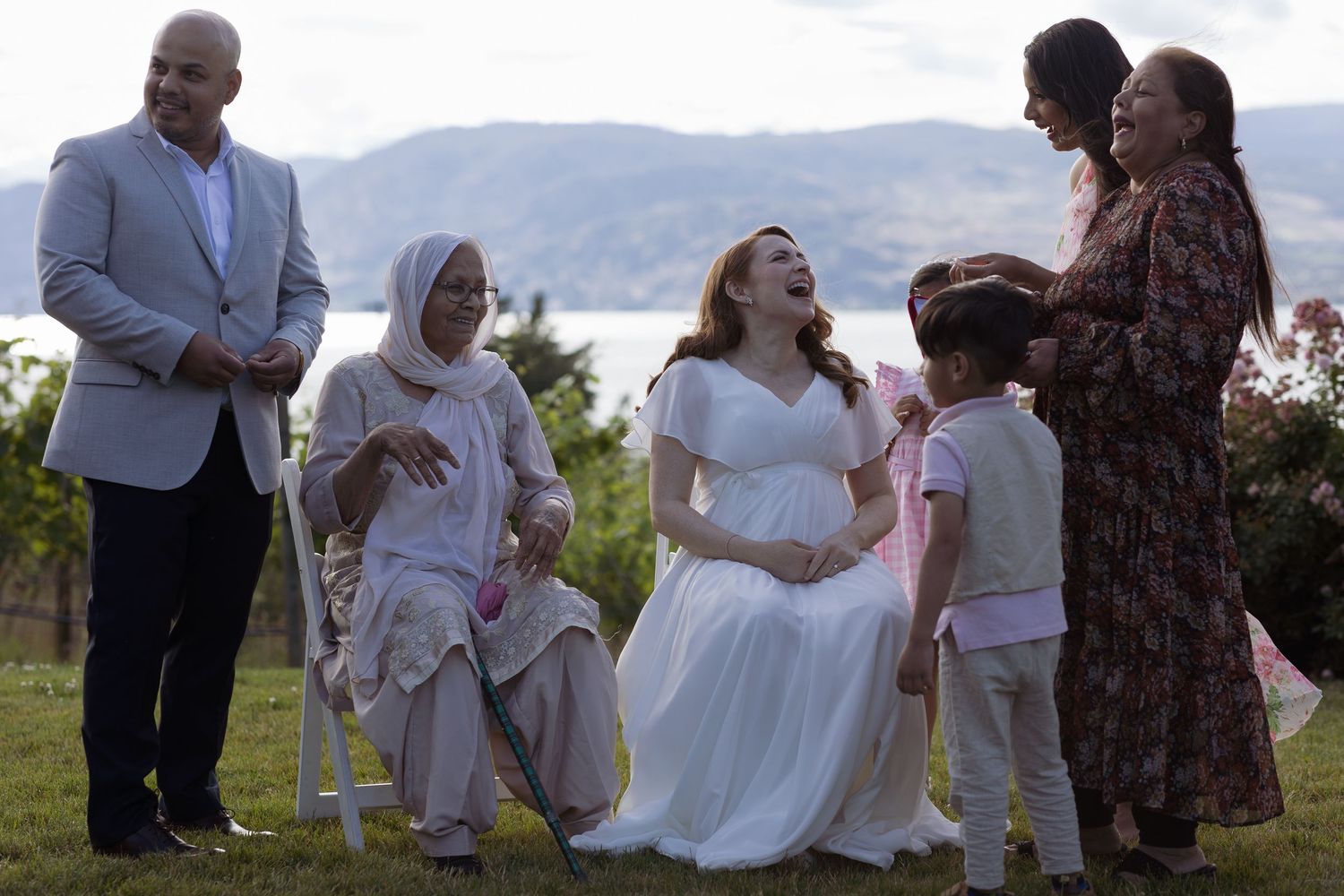 Wedding guests dance and celebrate at an outdoor reception with mountains visible in the background.