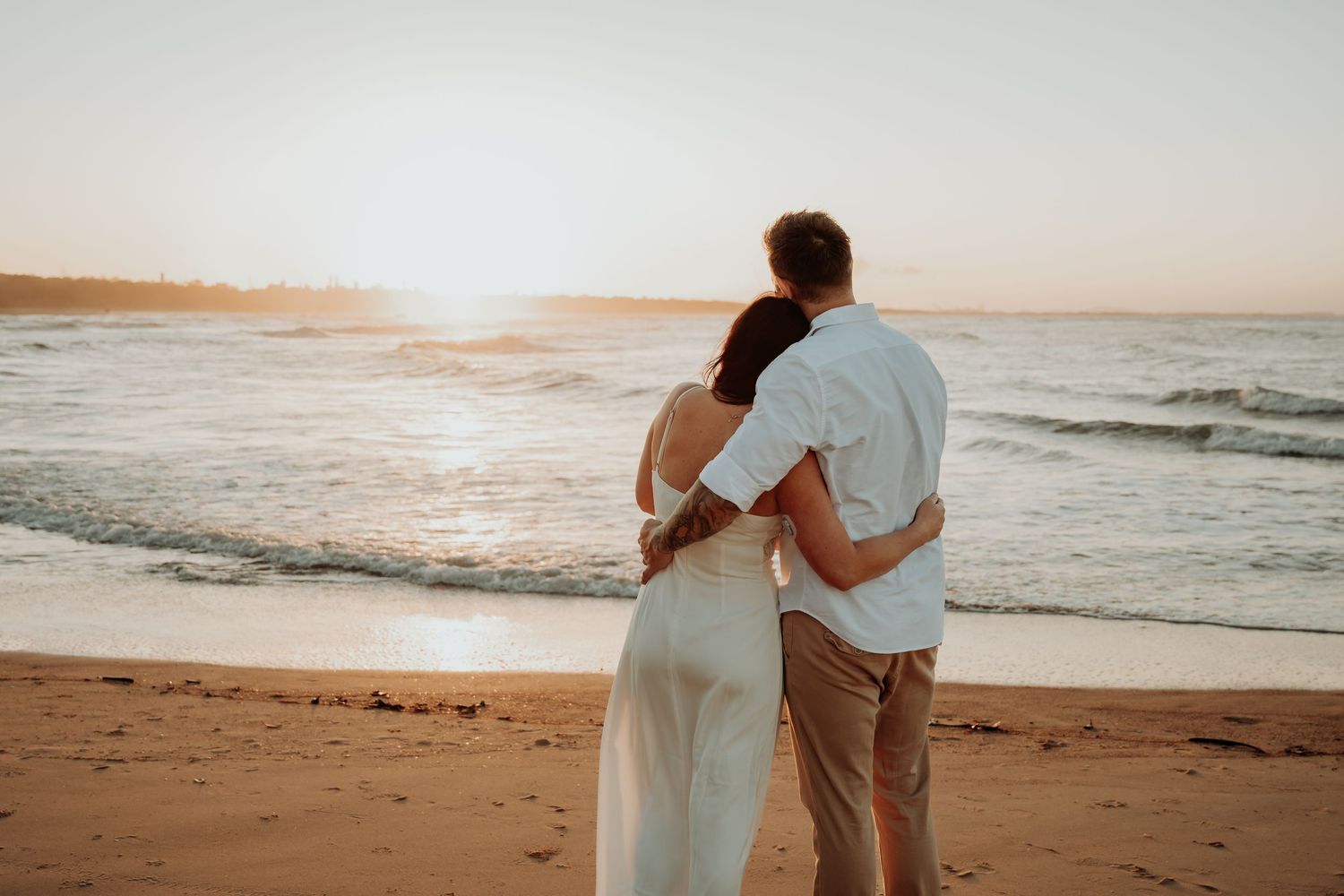Couples walking along tannum sands beach shoreline during a romantic beach sunset.