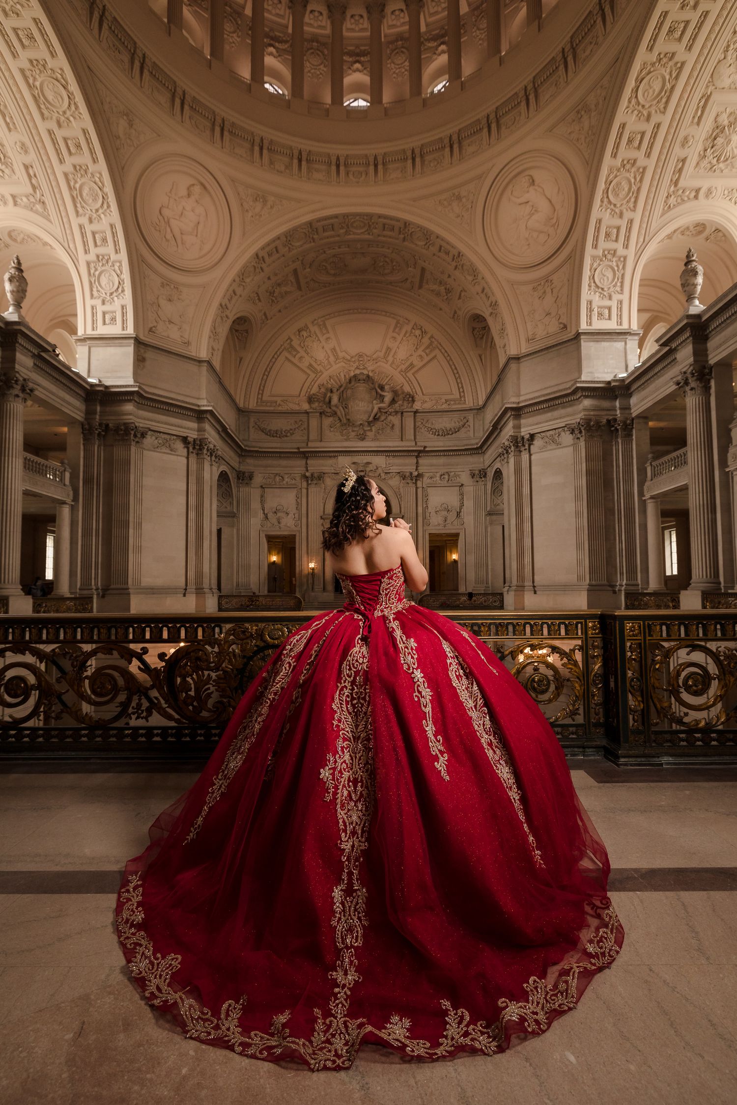 Majestic red ball gown with gold embellishments photographed in domed classical rotunda.