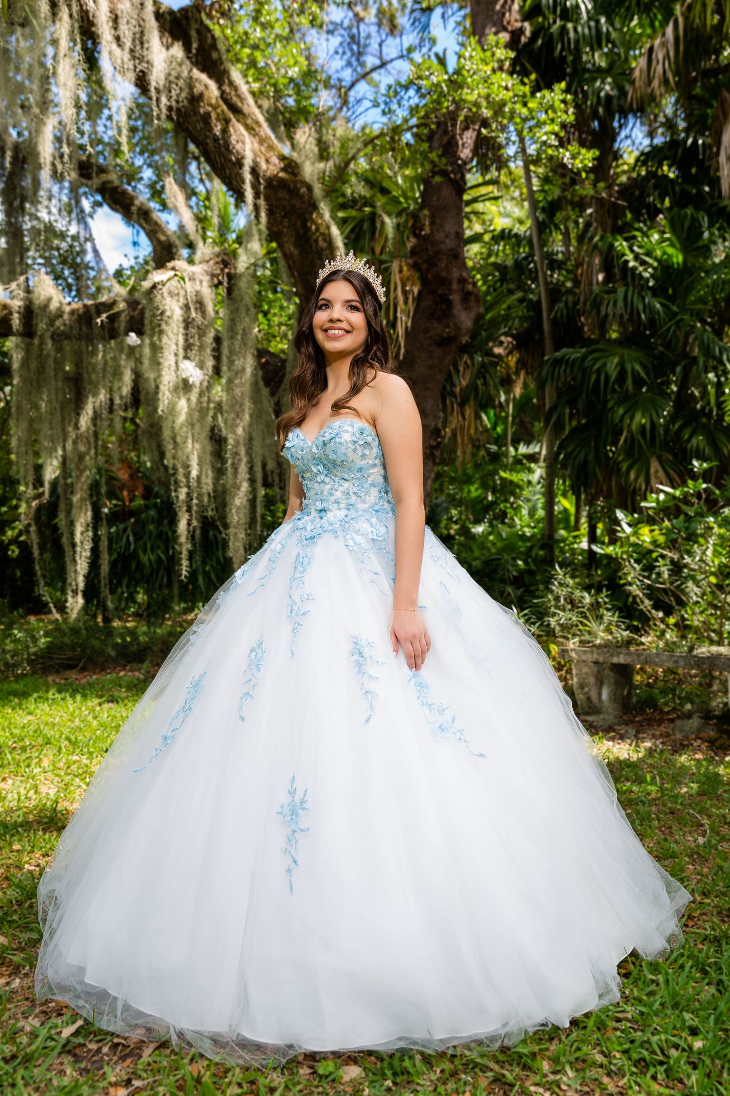 A stunning white and blue ball gown with tulle skirt photographed in a lush garden setting with Spanish moss.