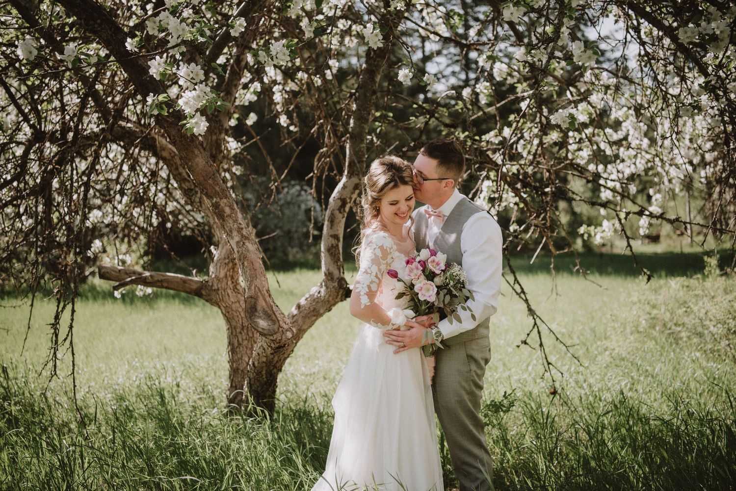 Bride and groom embracing in an orchard for their wedding photos. Okanagan photographer