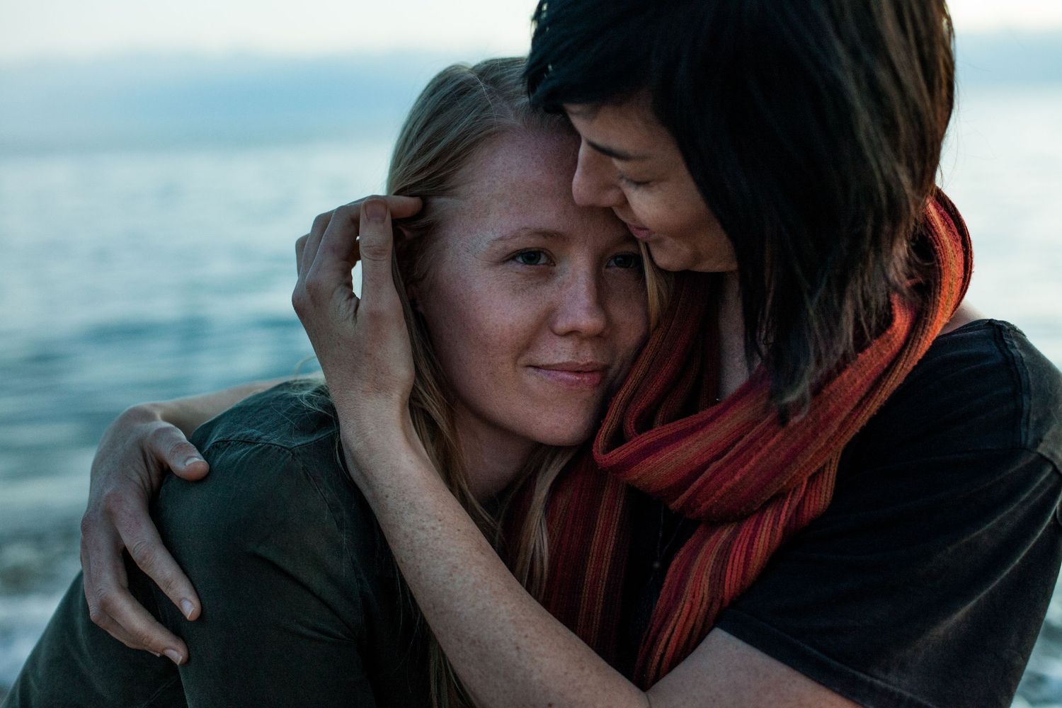 Intimate couple portrait captured at sunset by the ocean with warm lighting.