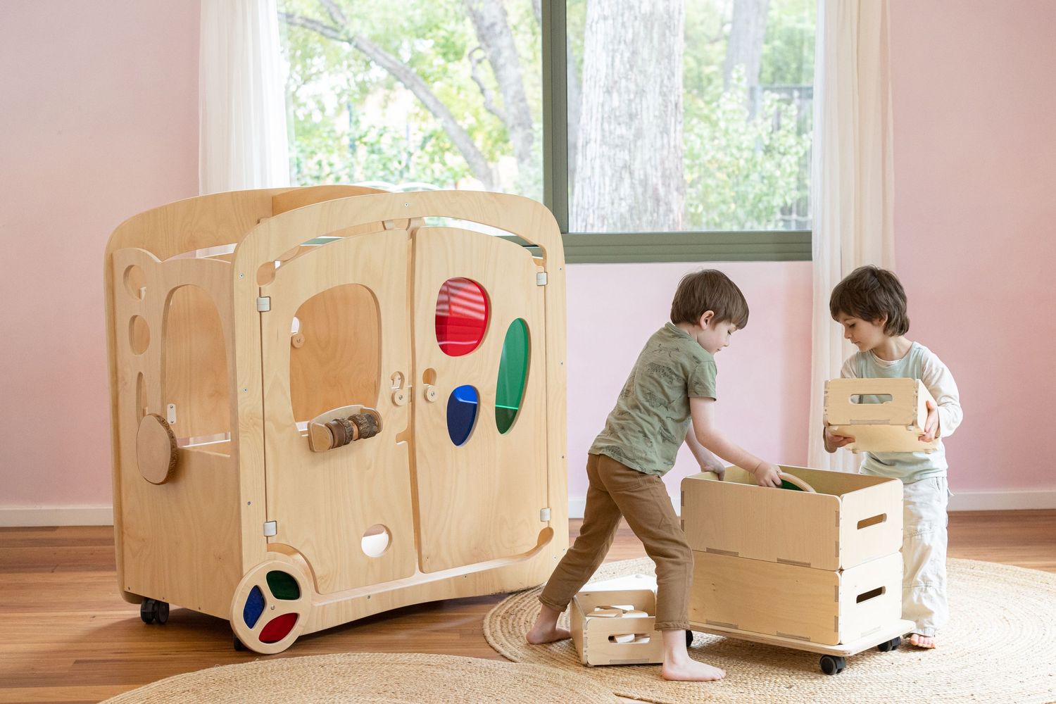 Two children playing with wooden storage boxes in sunlit room.