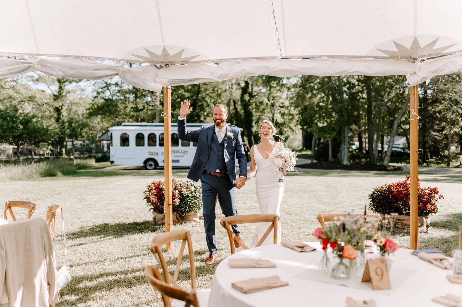 An elegant outdoor wedding reception setup with white tents and rustic wooden chairs.