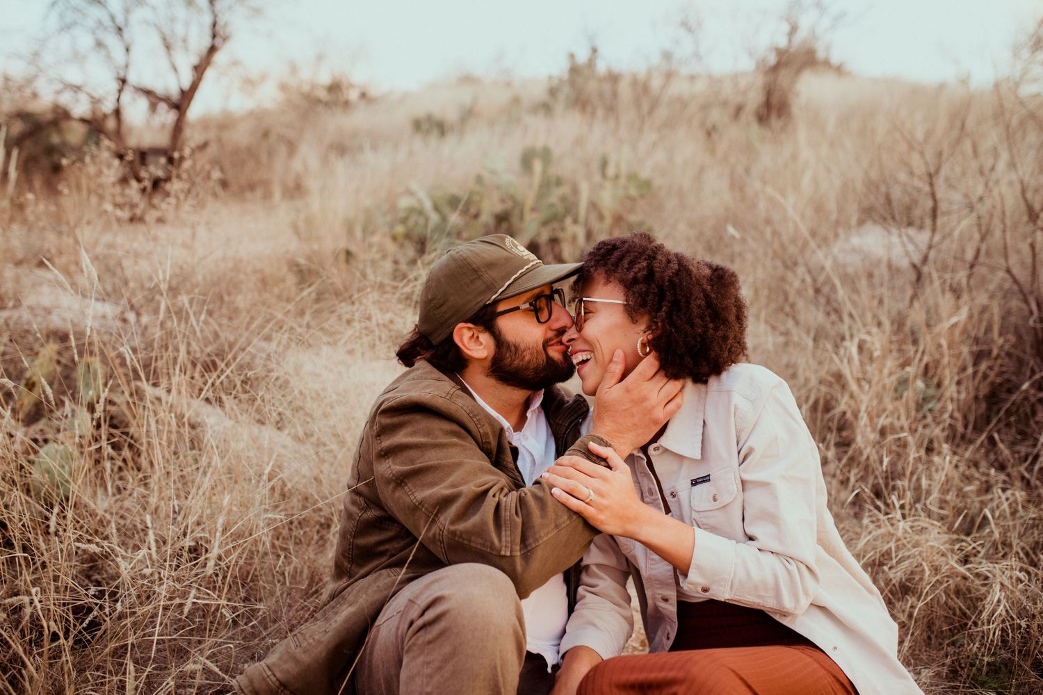 Intimate moment between couple sharing affection while sitting outdoors in natural setting.