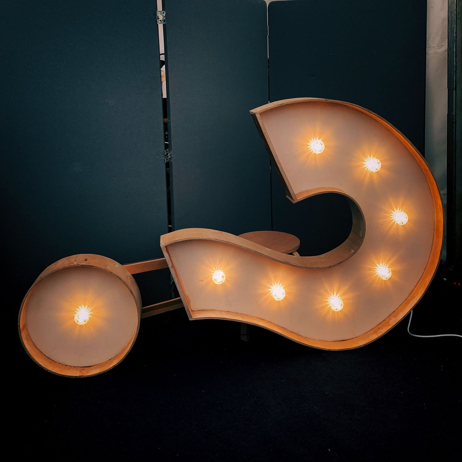 Illuminated curved question mark signs against a dark background.