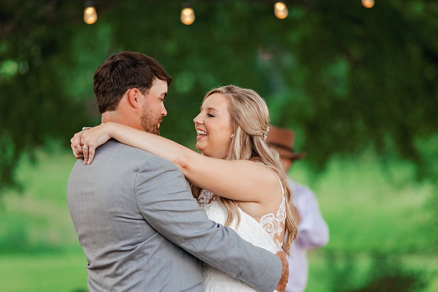 Happy couple shares intimate dance moment during outdoor wedding celebration.