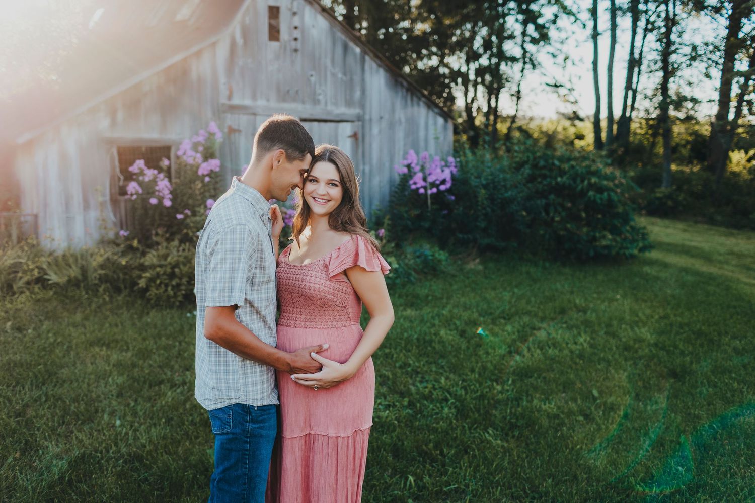 Maternity photo with soft sunset lighting in rustic outdoor setting.