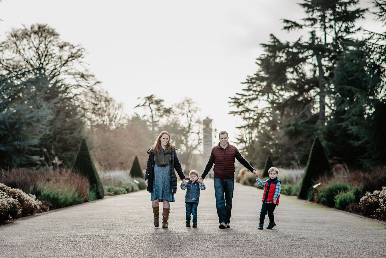 Family walking together on a scenic garden path during sunset.