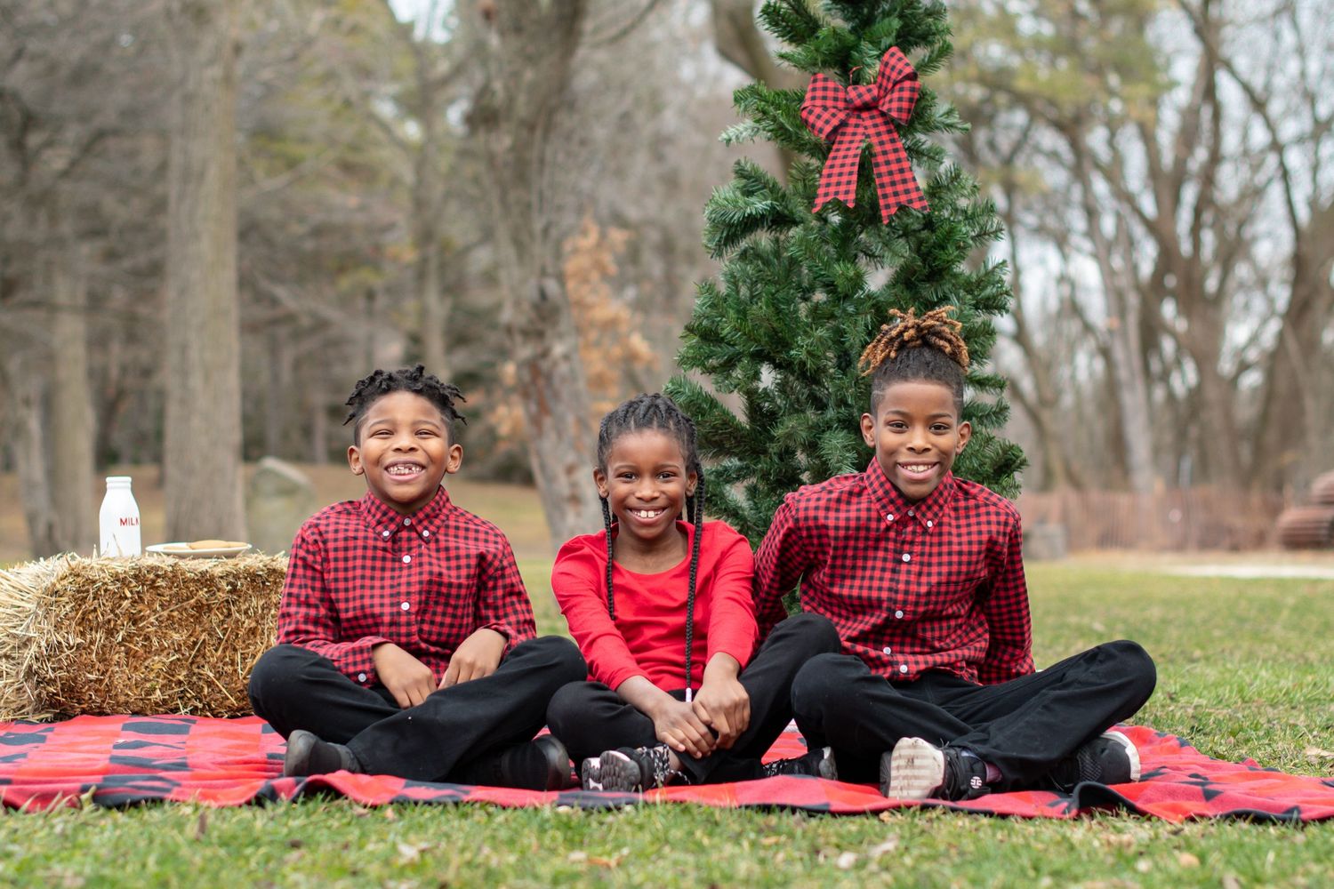 Family wearing coordinated red outfits sitting together on a blanket for holiday photos.