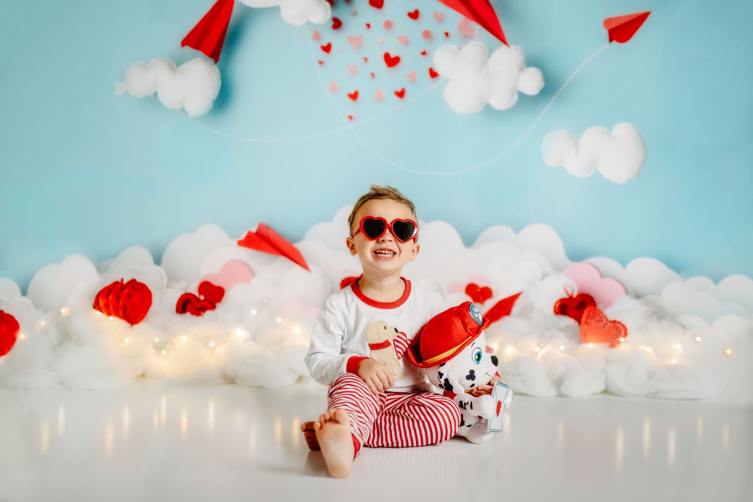little boy in valentine outfit and glasses in front of love note background, holding a stuffed Dalmatian puppy