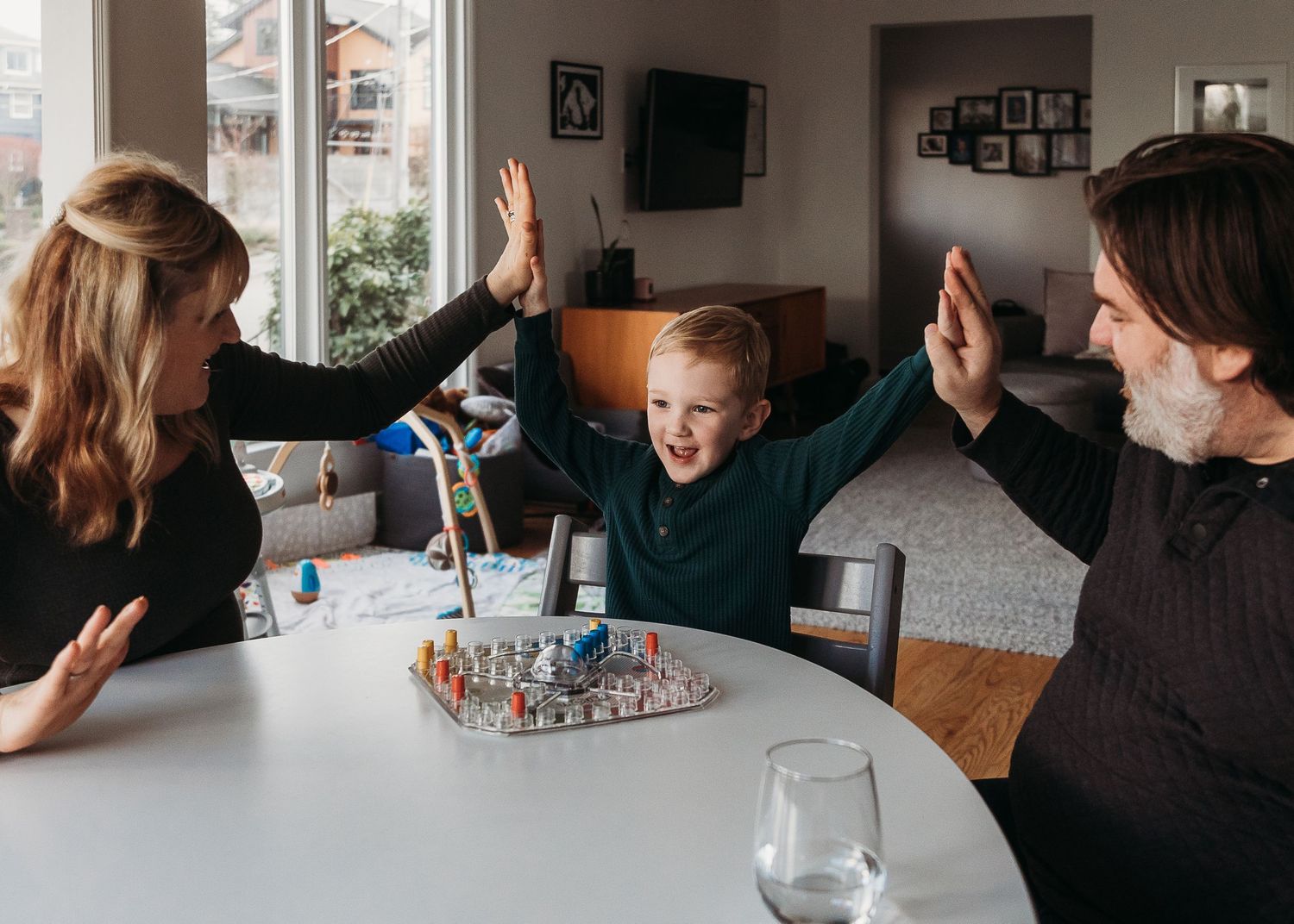 Celebrating at a table with a board game and high-fives all around.