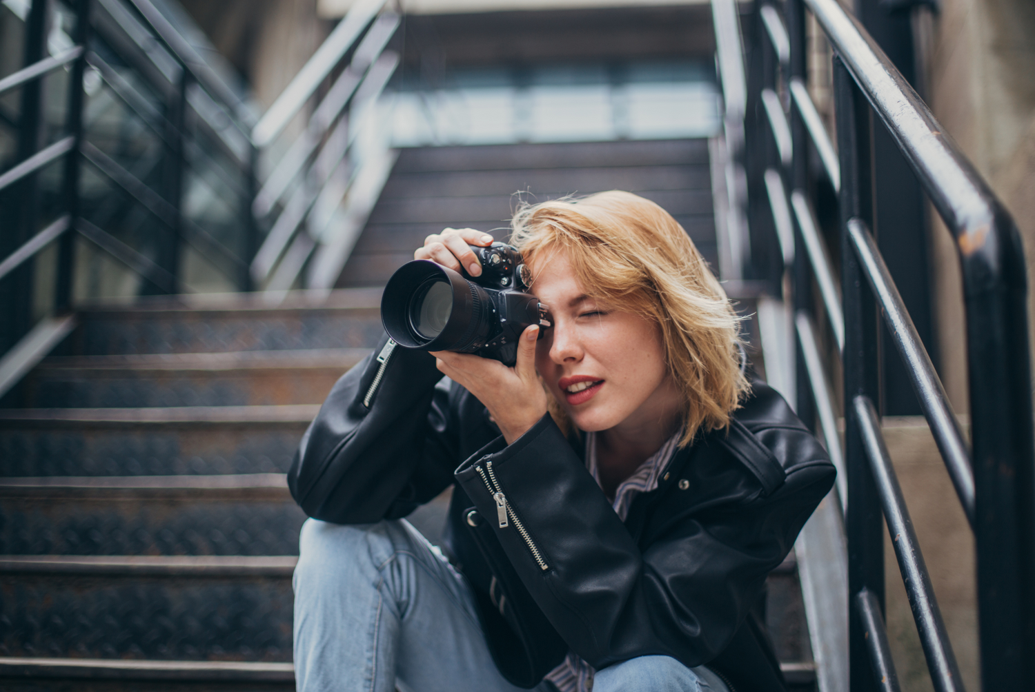 Photographer taking pictures while sitting on concrete stairs.