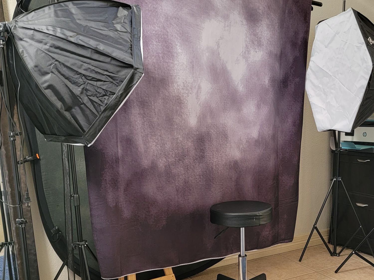 Professional photo studio with purple backdrop and lighting equipment setup.