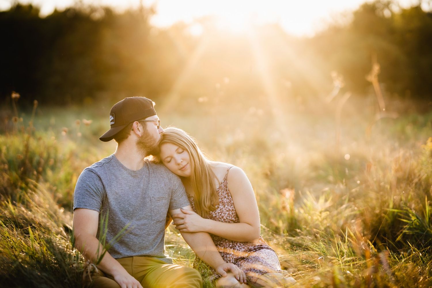 A woman leans on her boyfriend in front of a sun flare.