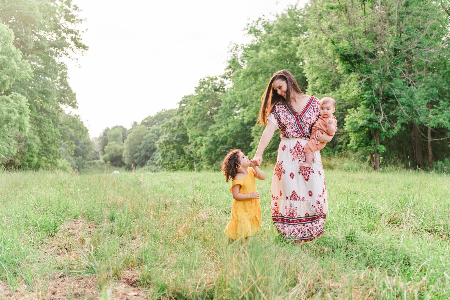 Mother and daughters walking through field in golden hour sunlight in Pittsburgh, Pennsylvania