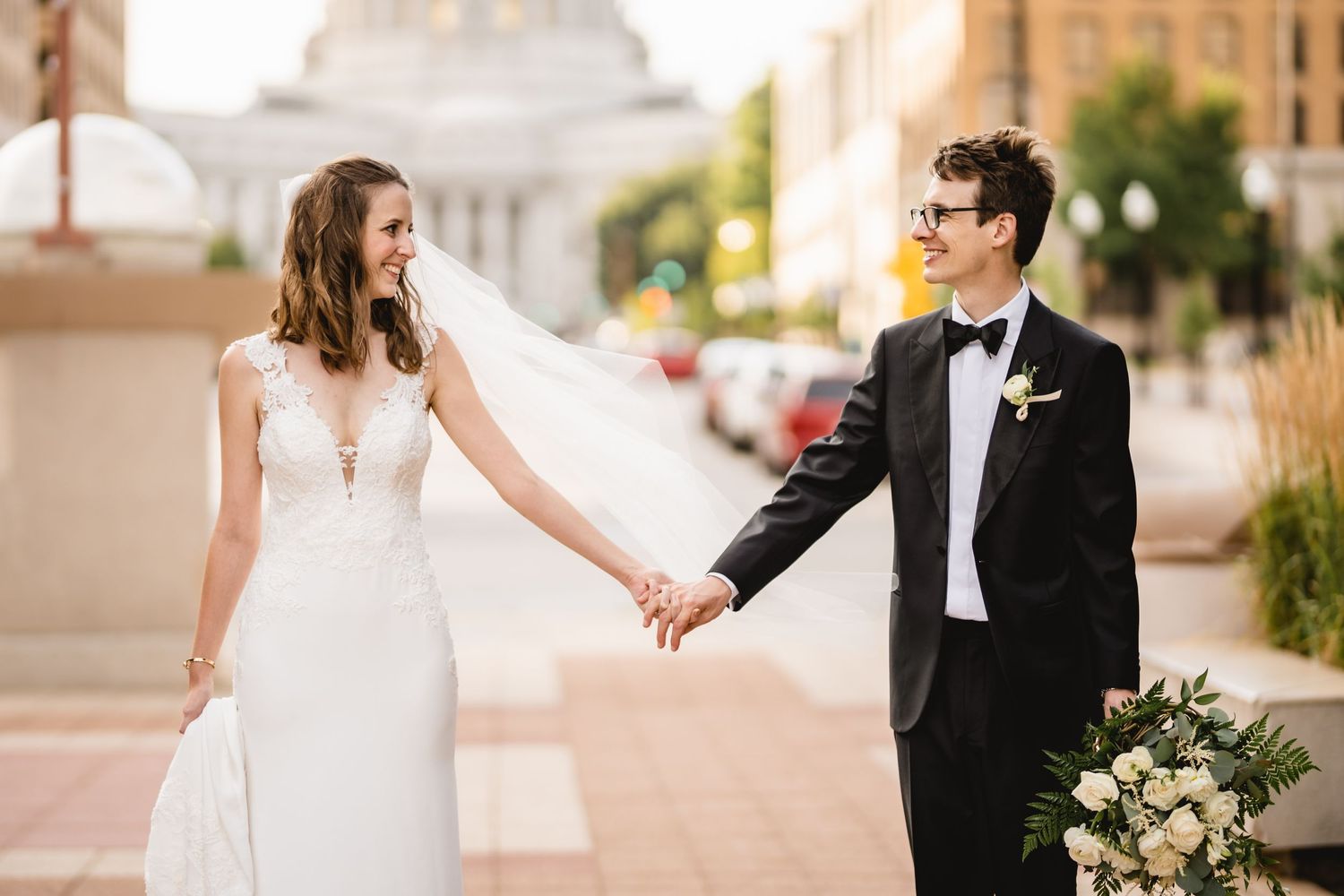 A smiling bride and groom in front of the Wisconsin State Capitol building