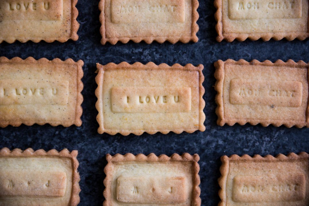 Overhead view of homemade shortbread cookies with 'I LOVE U' text imprinted on each biscuit.