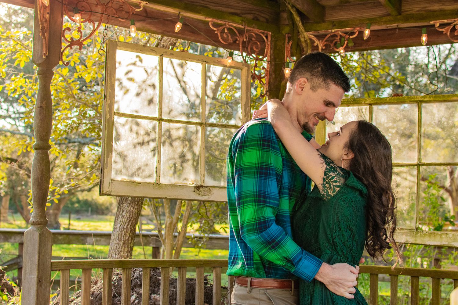 Romantic couple holding each other close in gazebo during fall season.