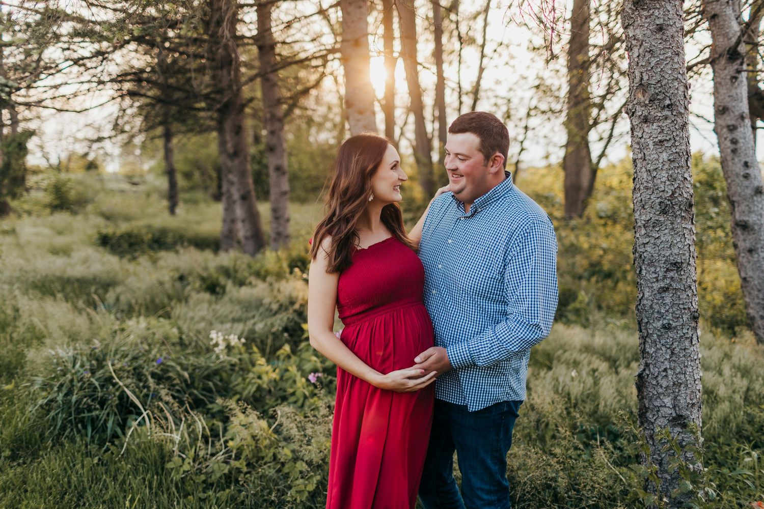 A couple photographed during sunset among birch trees in a natural outdoor setting.