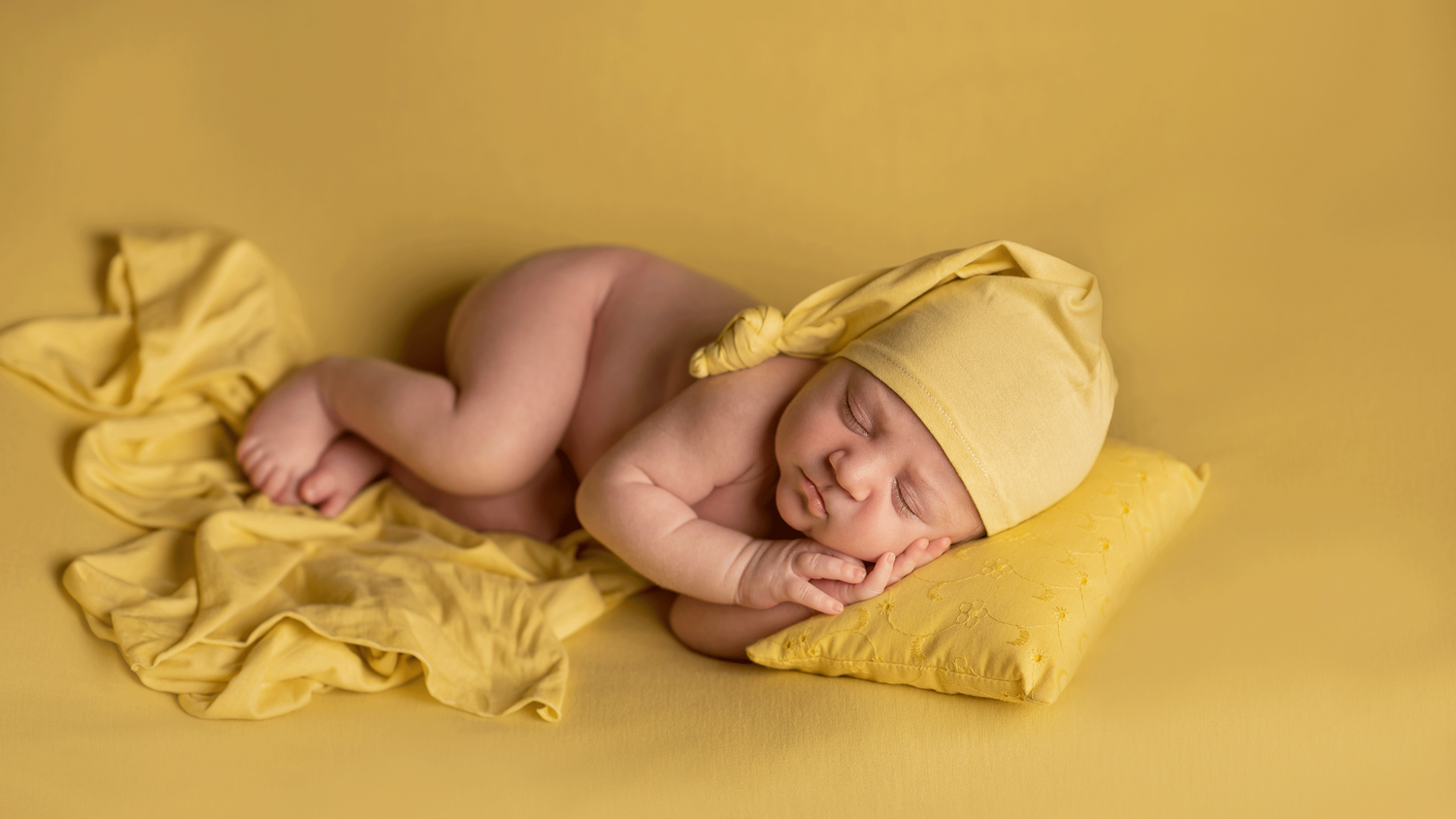 neonato-giallo-dorme-cappellino-cuscino-fotografia