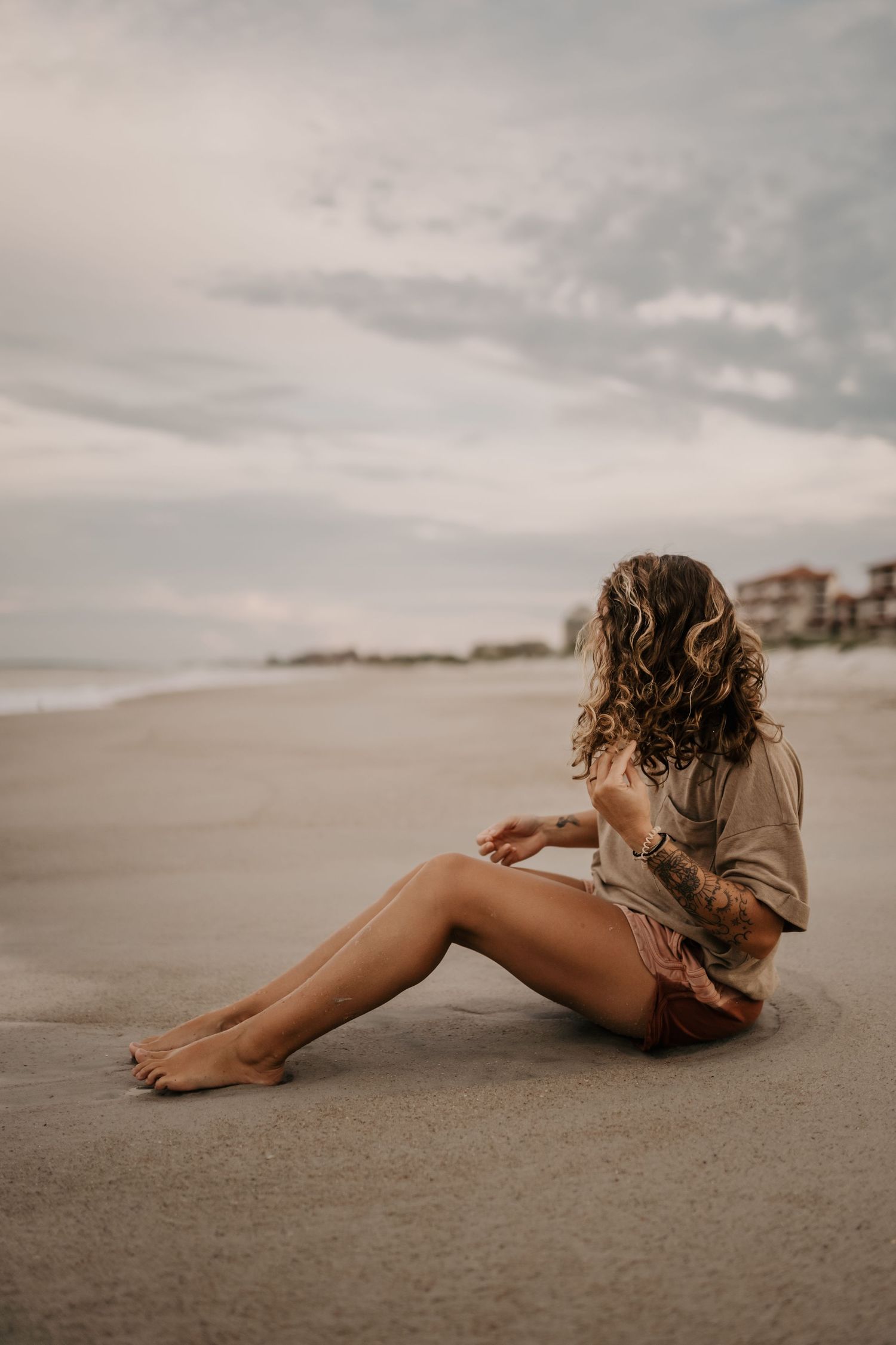 Someone sitting alone on a peaceful beach at sunset.