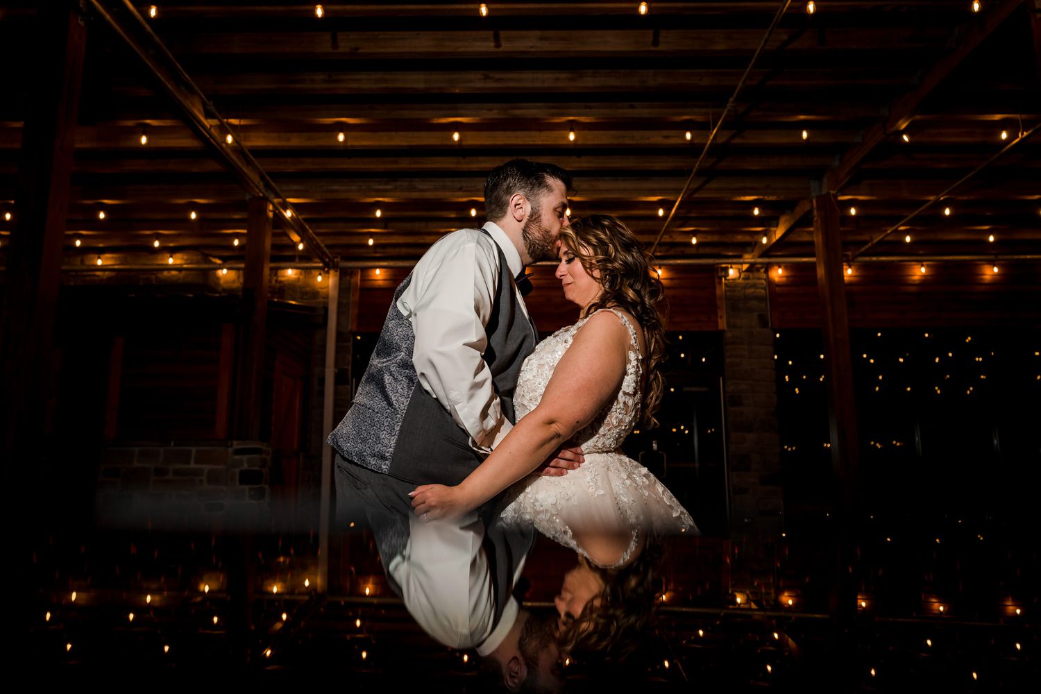 A couple dances together in a dimly lit venue with string lights overhead.