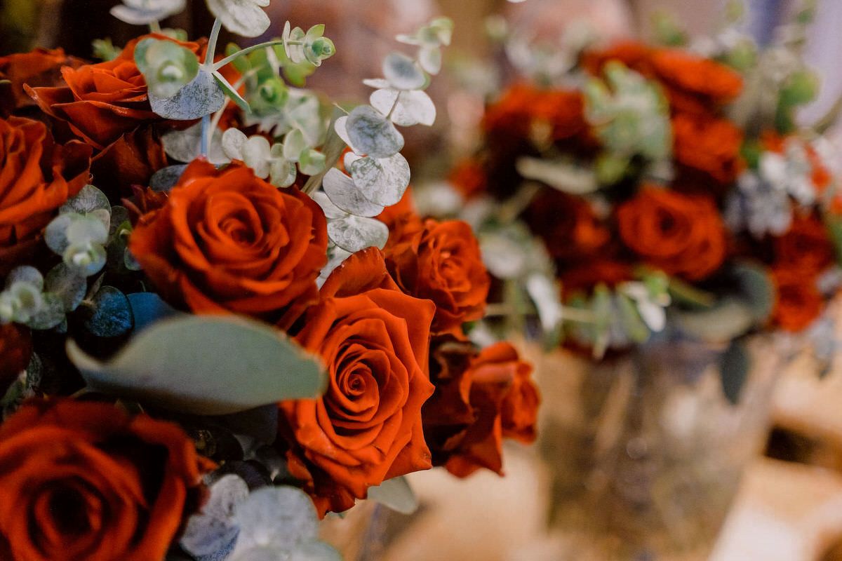 Elegant floral arrangement with vibrant red roses and delicate white flowers on a rustic surface.