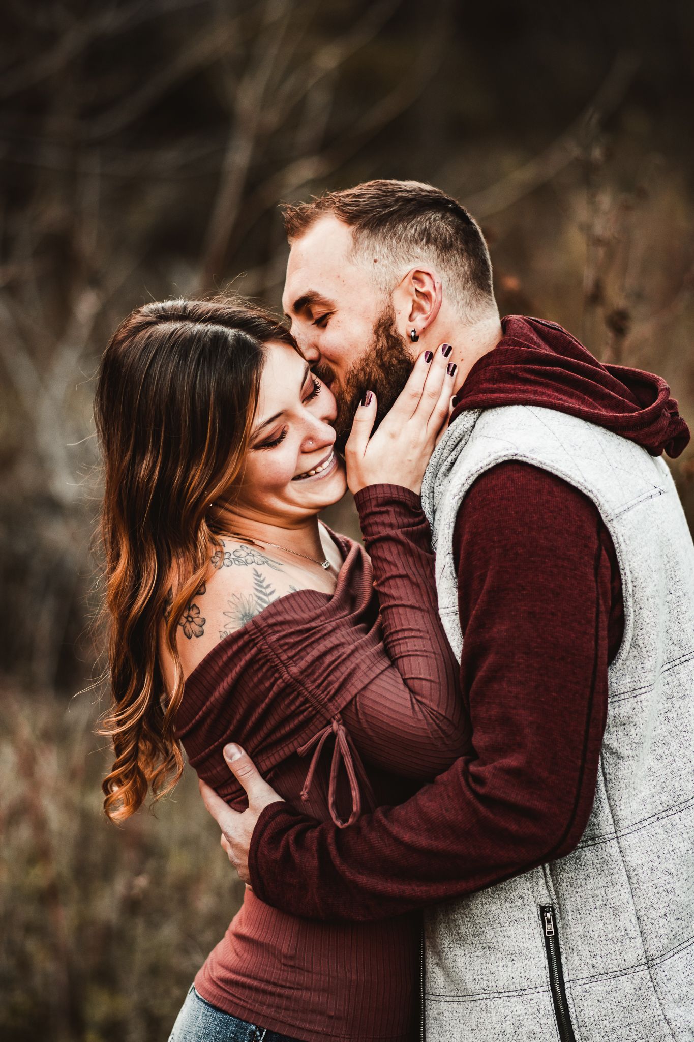 An intimate outdoor portrait showing tender affection against a moody natural backdrop.