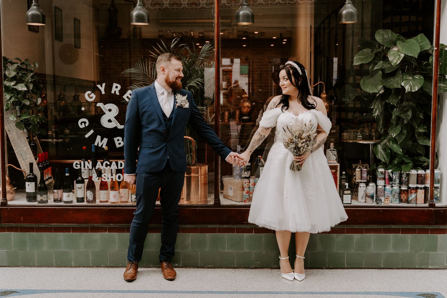 couple standing in a shopping mall outside a shop. Holding hands smiling at each other