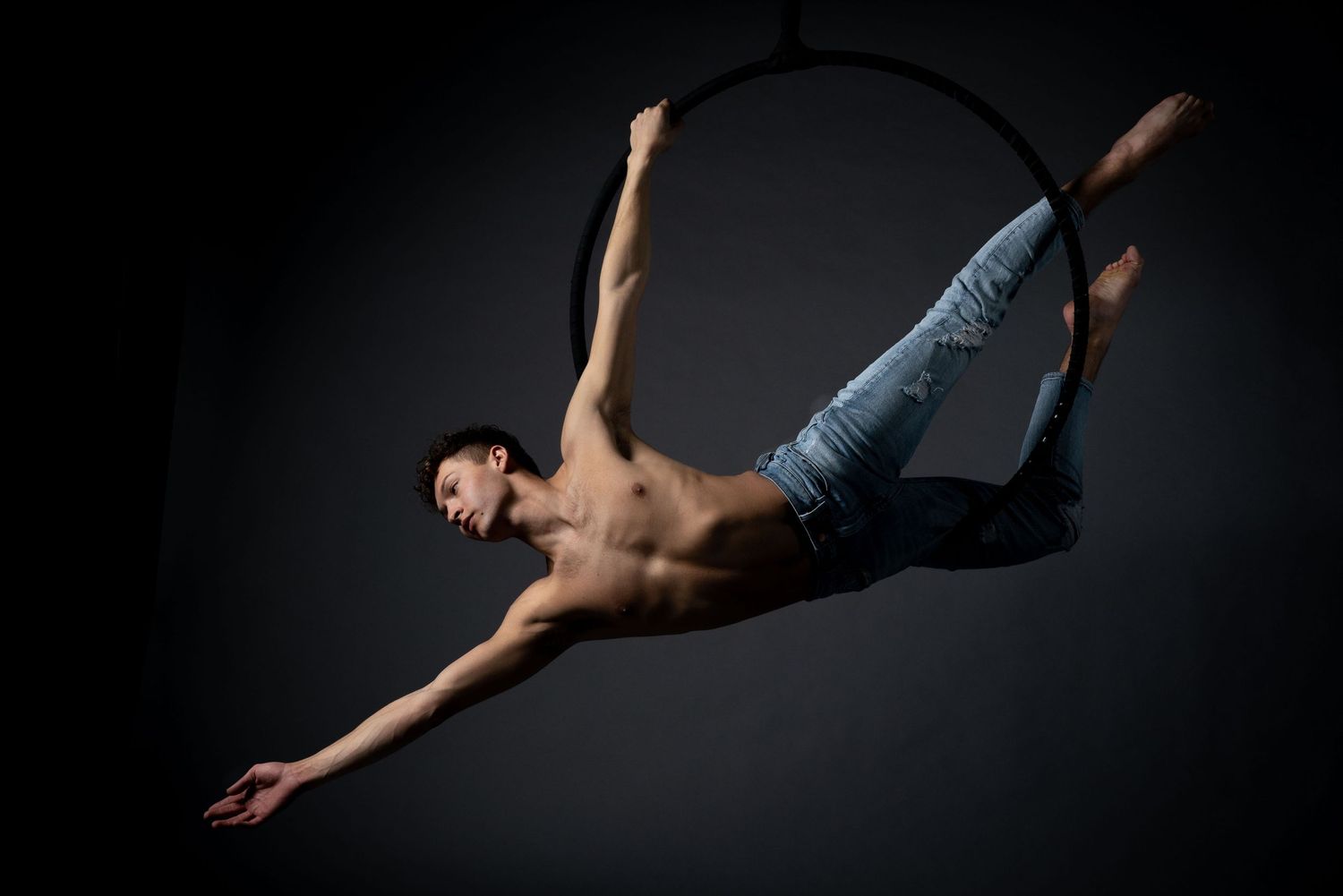 performances photography of a circus performer on a hoop wearing jeans and no top