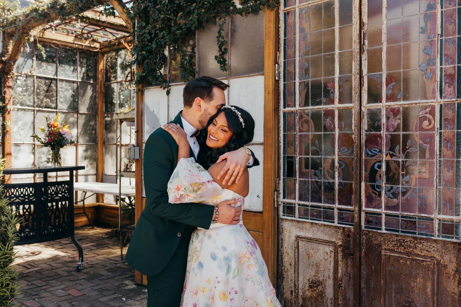 A romantic couple shares intimate moments in a rustic greenhouse setting with natural lighting and vintage windows.