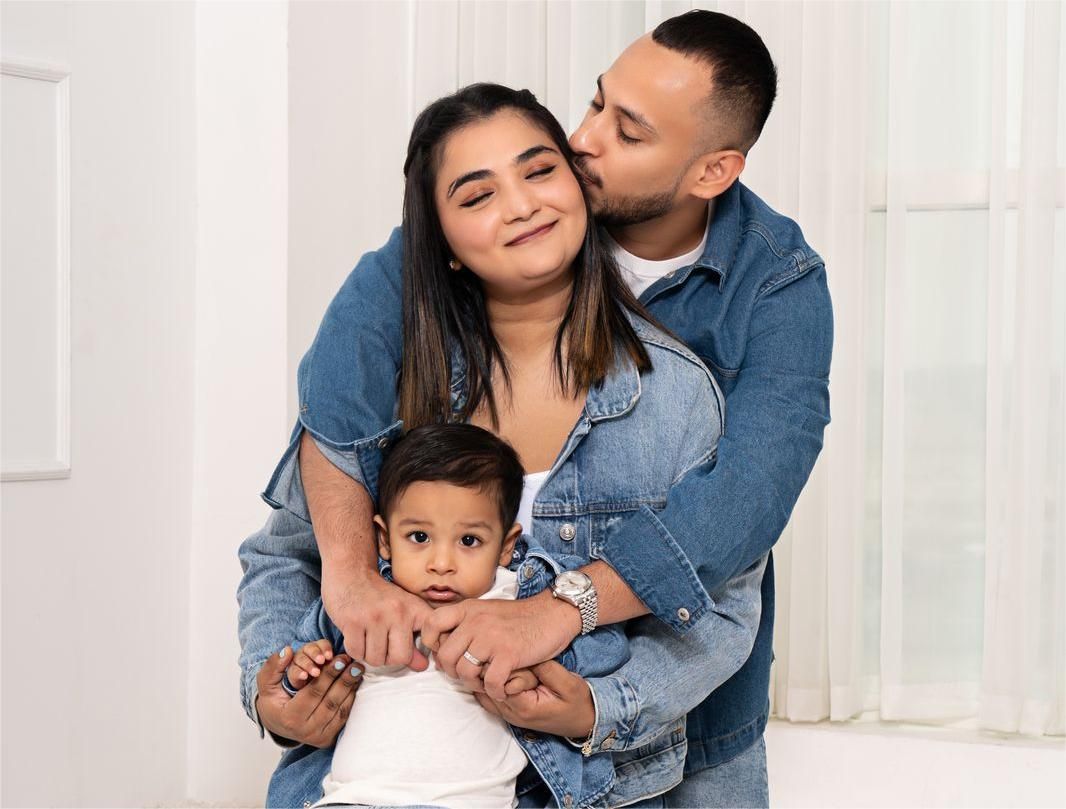 Family portrait showing intimate moment in white studio setting.