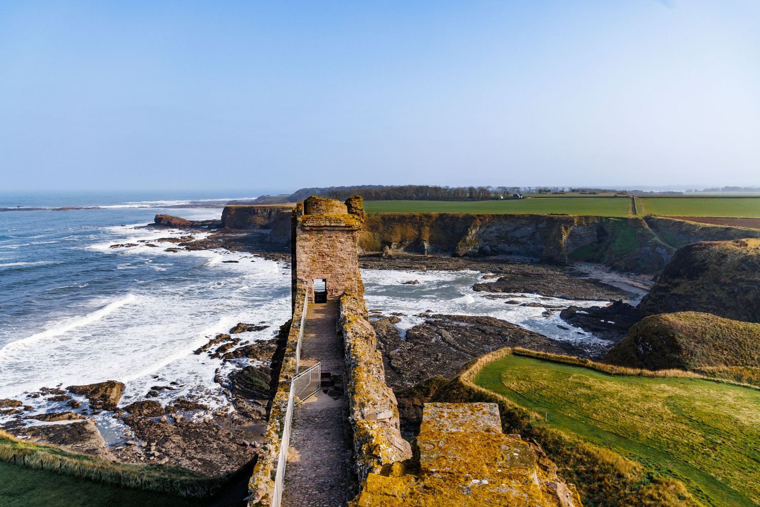 People exploring castle walkway above the sea