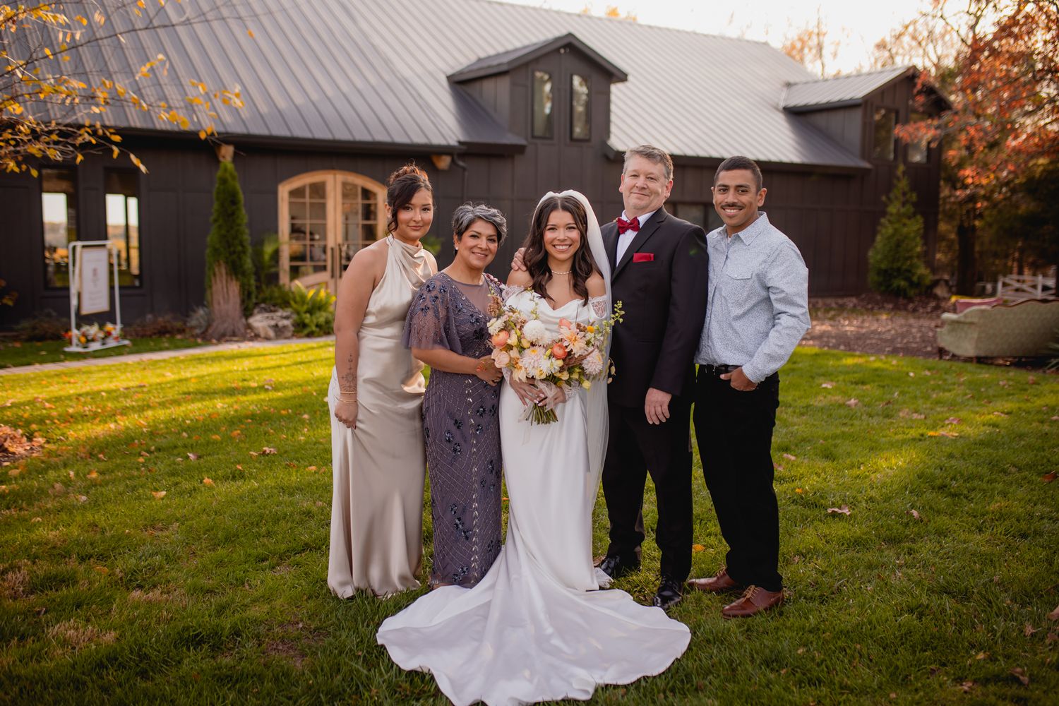 Bride with her parents and siblings smiling together outside Graystone Valley wedding venue in Walnut Shade, Missouri, capturing joy!