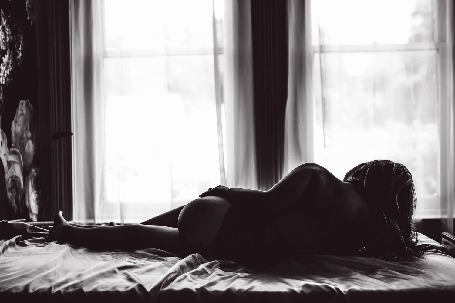 A black and white silhouette of a woman posing at a boudoir studio.