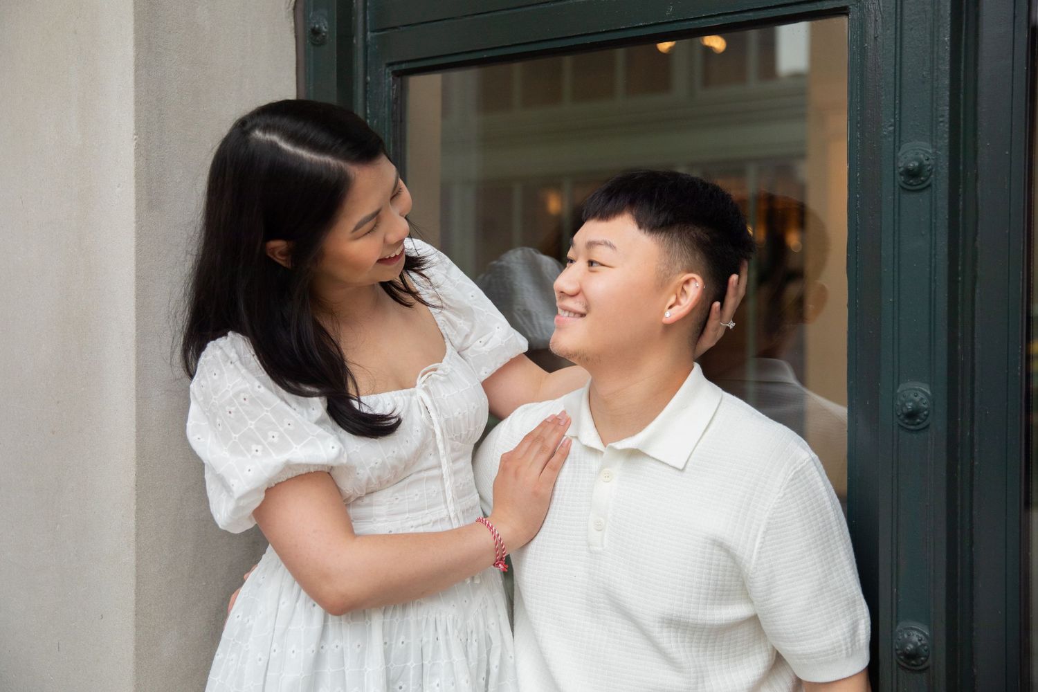 A couple shares an intimate moment by stone columns of a grand building during their engagement photoshoot.