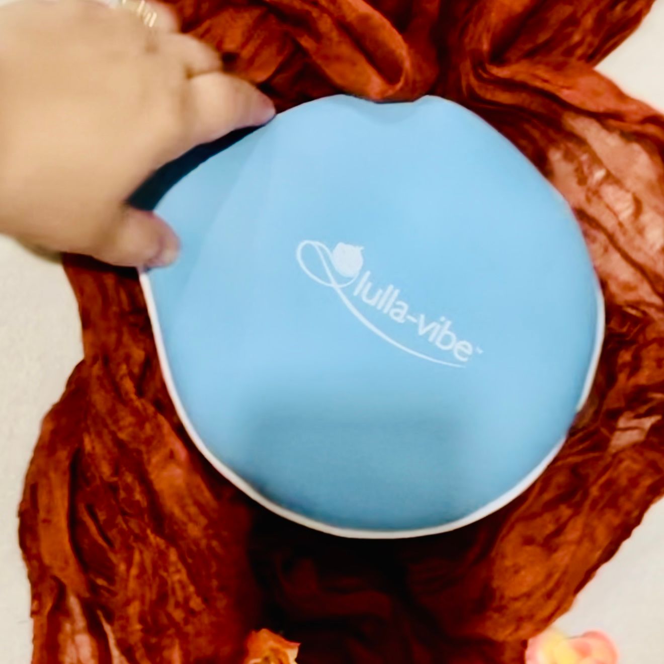 Blue egg-shaped massage therapy device shown in sequence being pressed into orange fabric demonstrating usage technique.