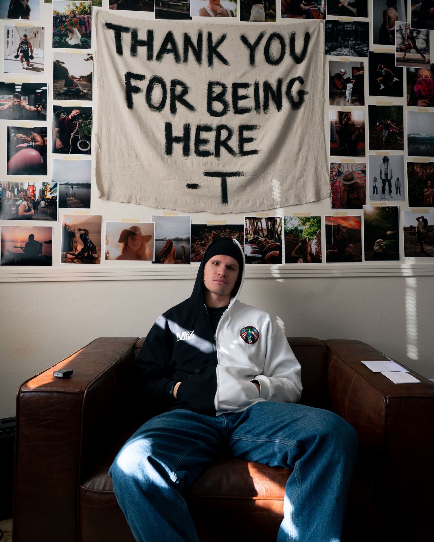 A series of Polaroid photos arranged on a wall with handwritten signs reading 'THANK YOU FOR BEING HERE' in a dark room.