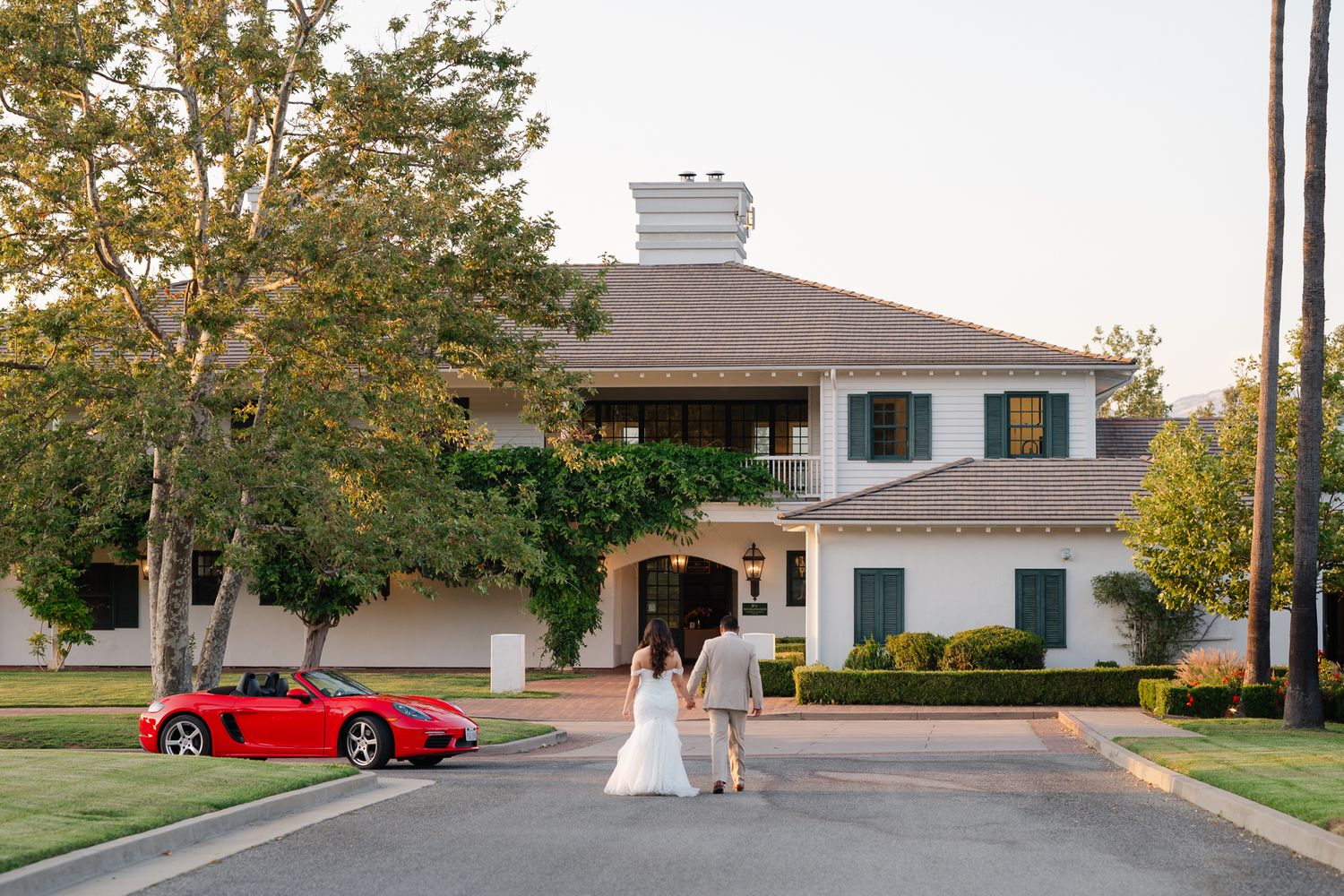 A red sports convertible parked against a scenic mountain backdrop at sunset creating a romantic silhouette.