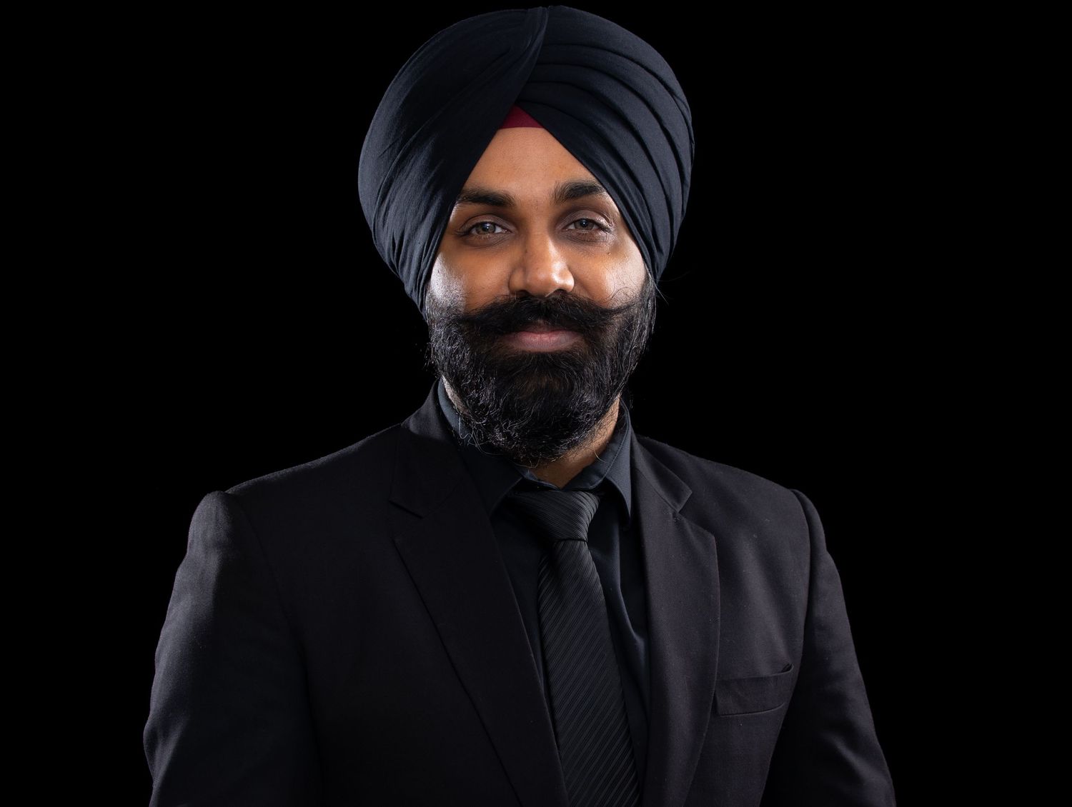 A series of seven portraits showing a real estate agent Ishdeep Singh in a turban and dark clothing against a black background.