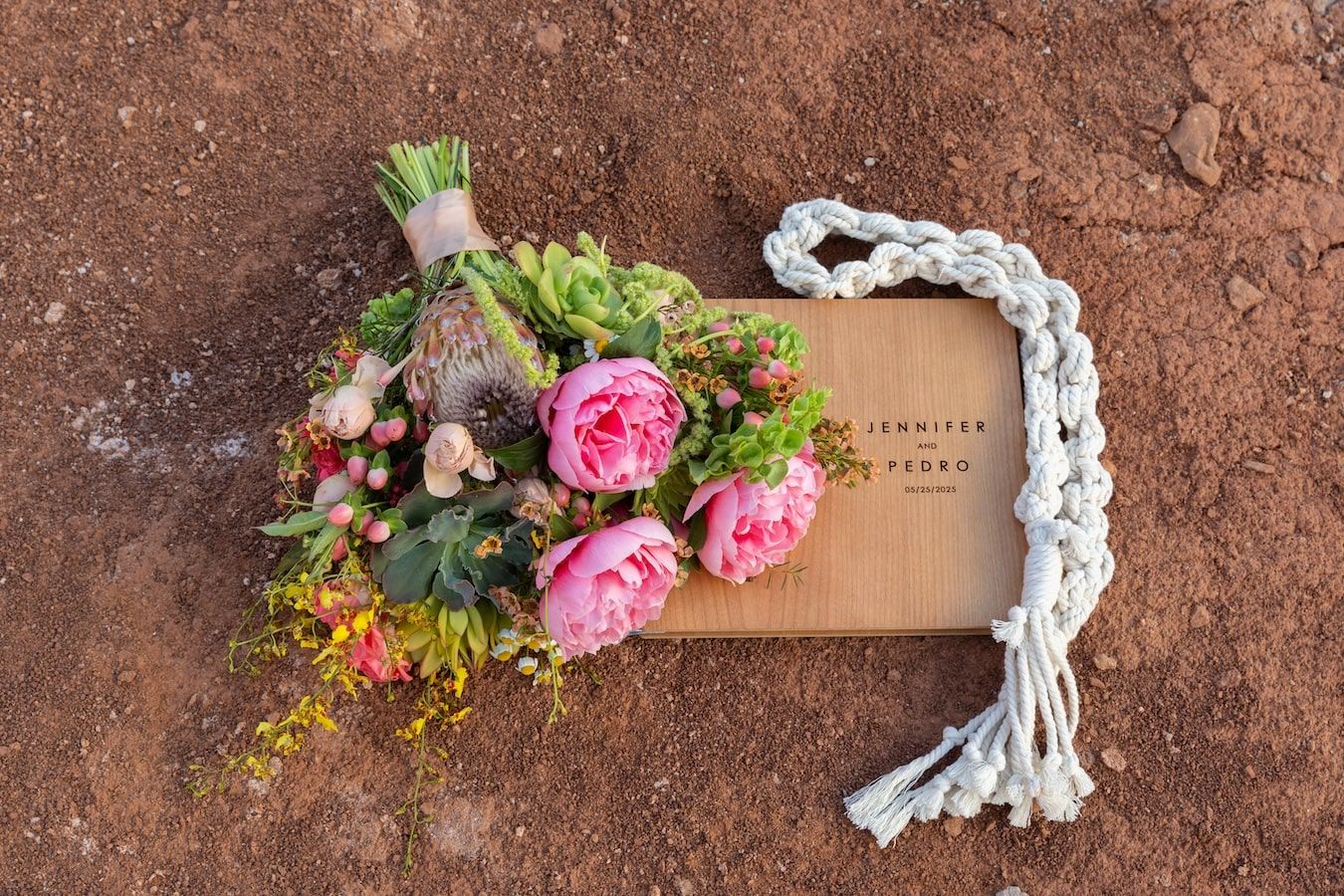 A floral decorative border pattern with pink peonies and fresh greenery arranged on rustic brown background.