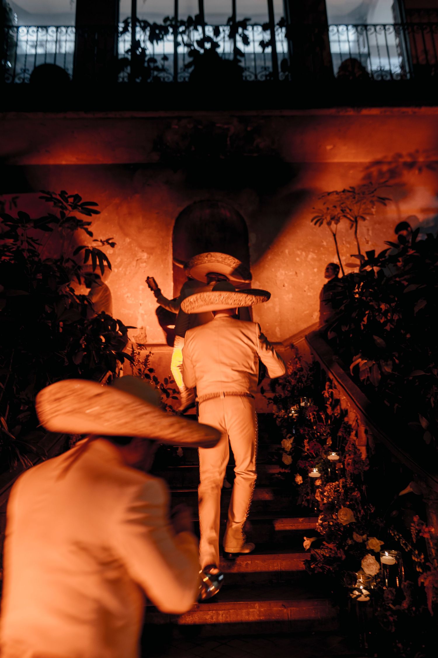 A sequence of dimly lit orange-tinted photos showing a figure in white clothing moving through a dark garden at night.