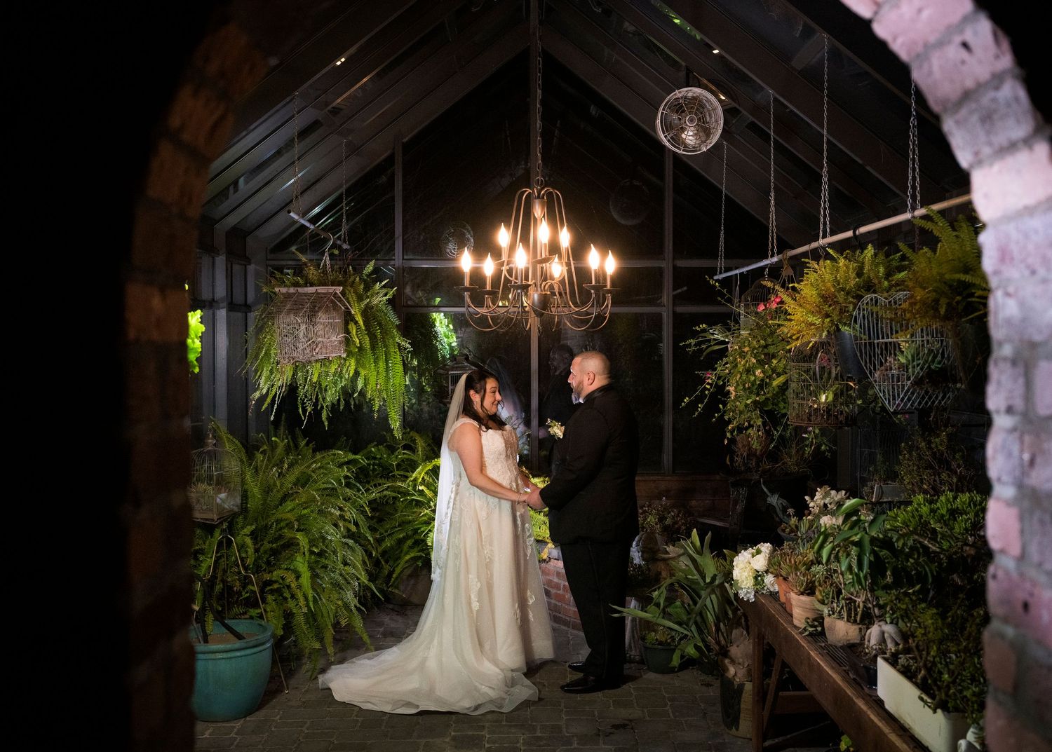 Newlyweds share an intimate moment outdoors with autumn foliage and rustic architecture in background.