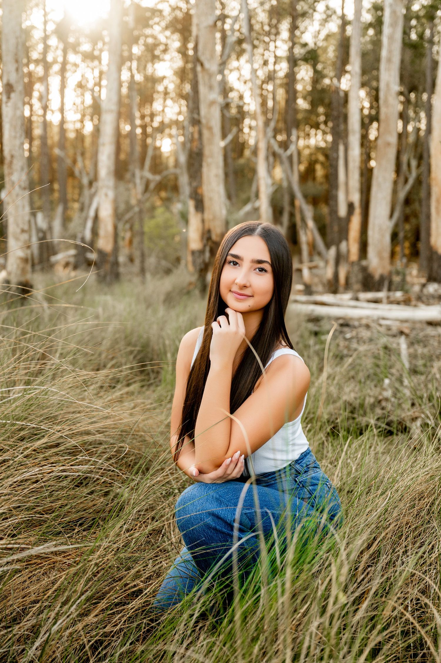 Natural light portrait session in tall grass with sunset filtering through trees.