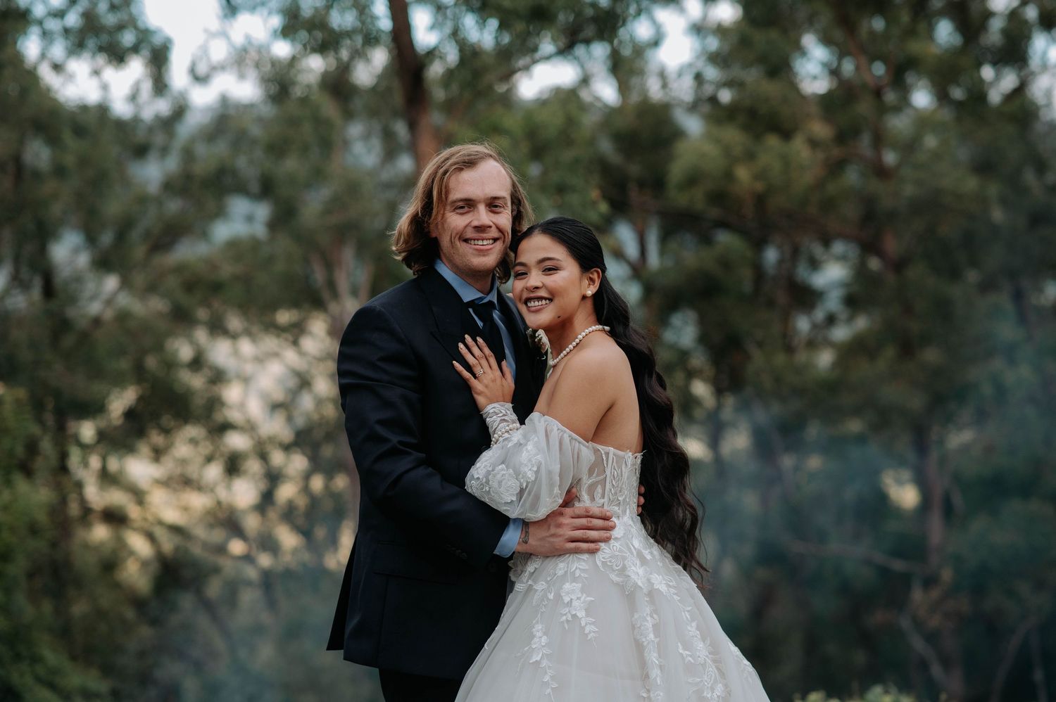 Happy couple embraces outdoors during their wedding photoshoot at a scenic garden location.